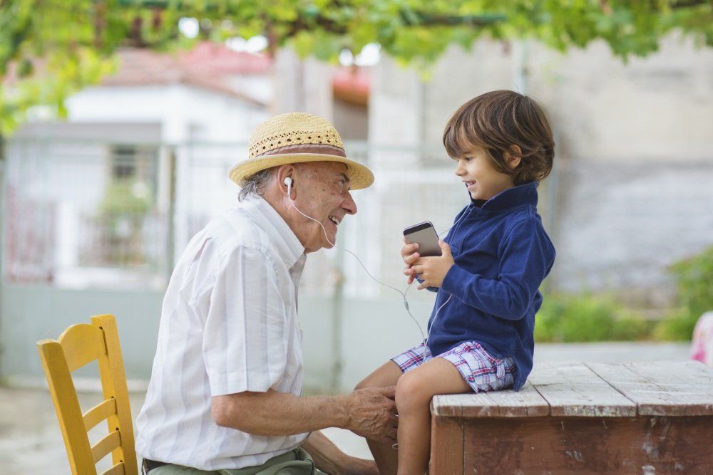 Un bambino che fa ascoltare la musica al nonno con un apparecchio acustico con cavi