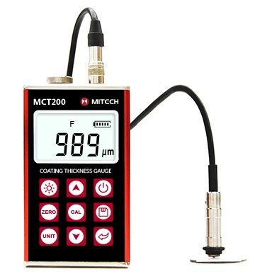 Un medidor de espesor de recubrimiento que muestra 989 µm. El dispositivo es rojo y negro, con una sonda conectada.