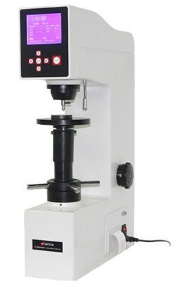 Un durómetro digital Rockwell, blanco, con panel de control negro y objeto de prueba sobre una plataforma.