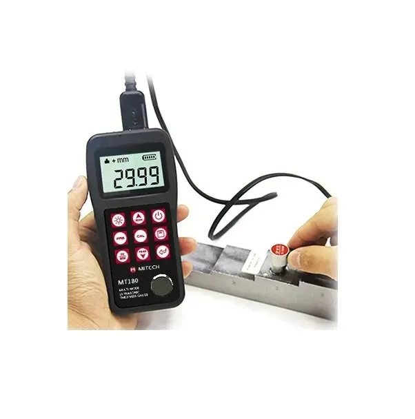 Mano sosteniendo un medidor de espesor ultrasónico negro con un cable conectado, midiendo un bloque de metal.