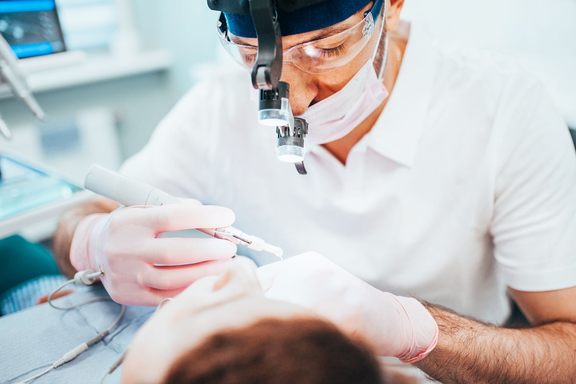View of a dentist examining a patient’s mouth using tools and light.