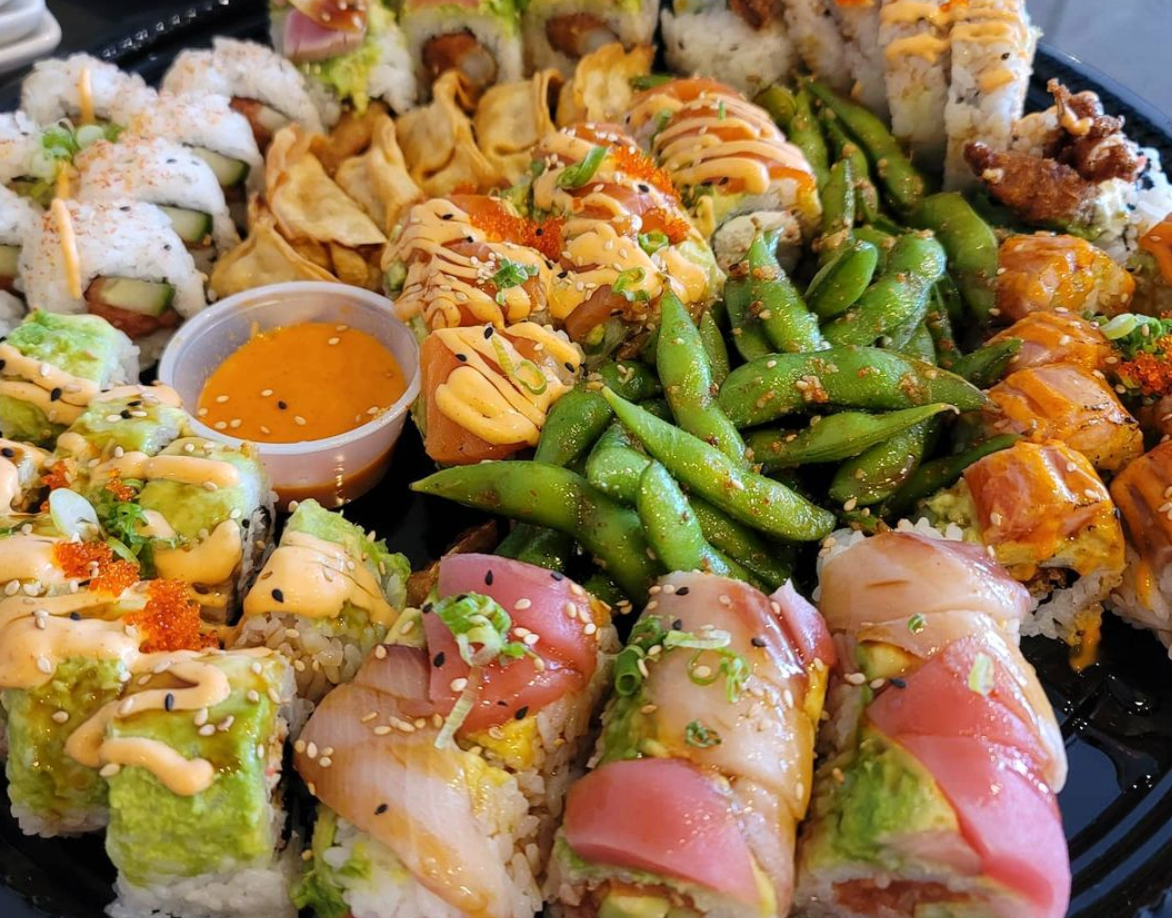 There are many different types of sushi and vegetables on the plate.