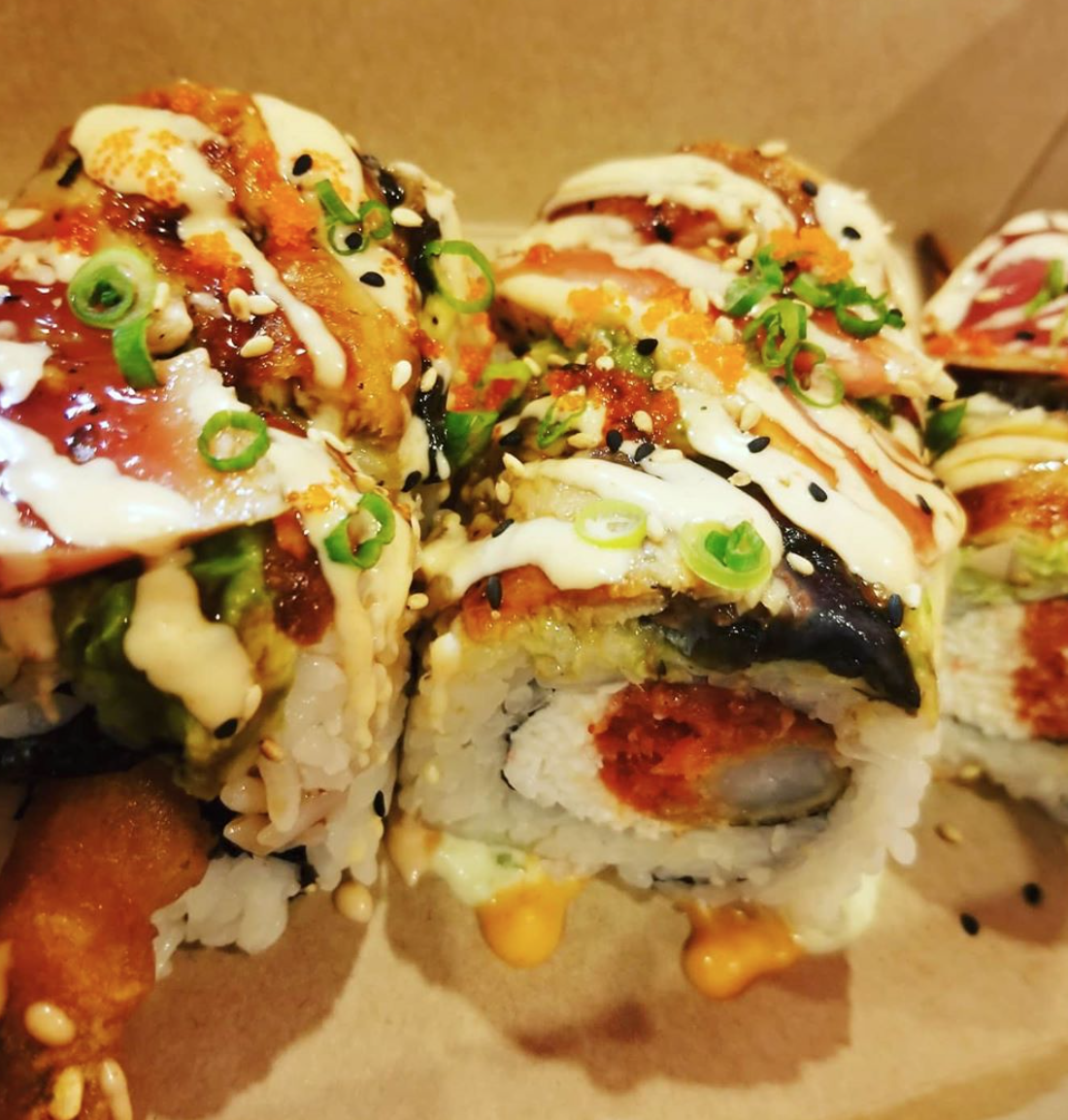 A close up of a sushi roll with sauce and green onions