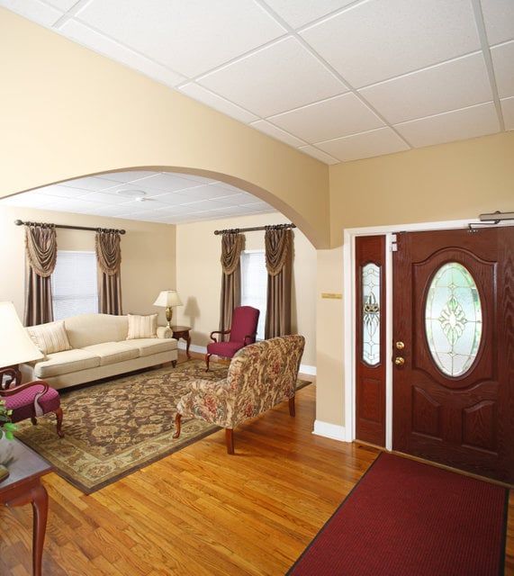 Living room with hardwood floors, a sofa, rug, and arched doorway. Mahogany door on the right.