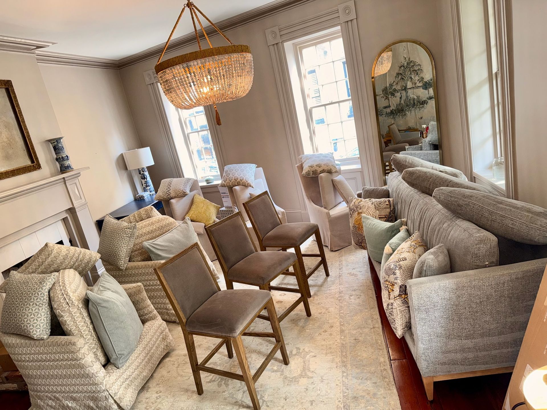 Beige sofa with multiple pillows of various colors and patterns. A wooden side table and lamp are in the background.