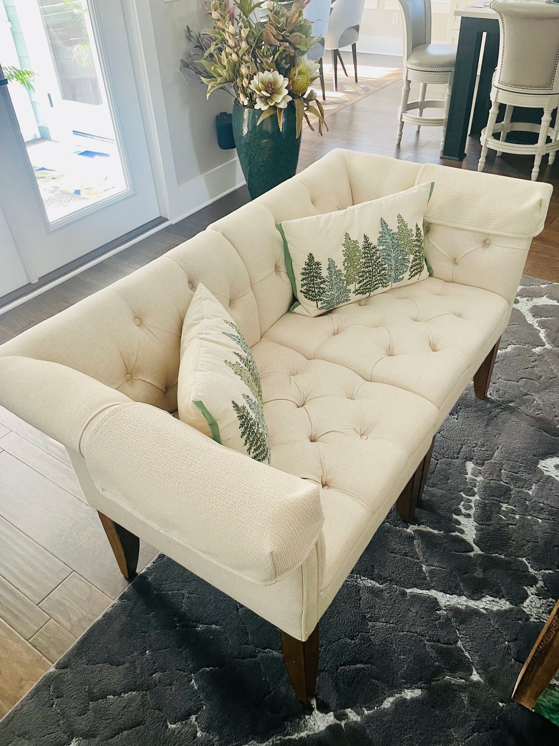 Beige sofa with several pillows on a light wood floor, angled view.