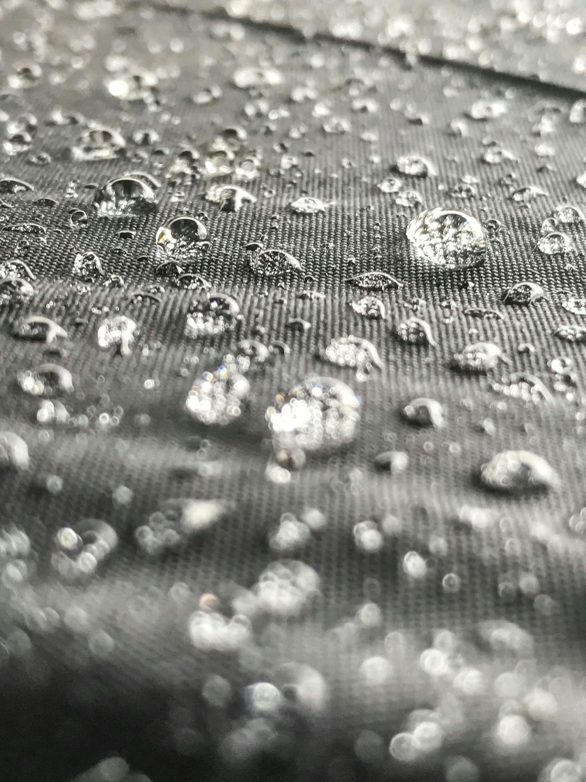 Wrinkled silver fabric with water droplets, reflecting light.