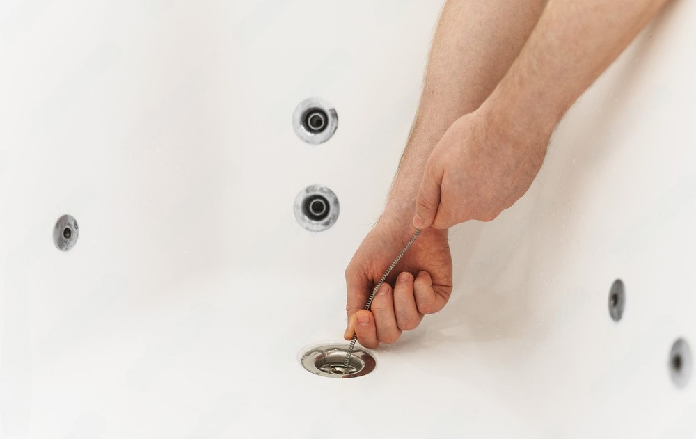 A man is fixing a bathtub with a wrench.