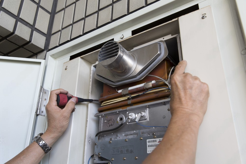 A person is fixing a heater with a screwdriver