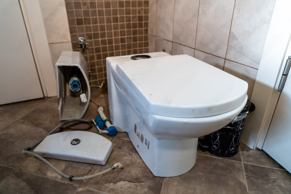 A toilet is sitting on a tiled floor in a bathroom.