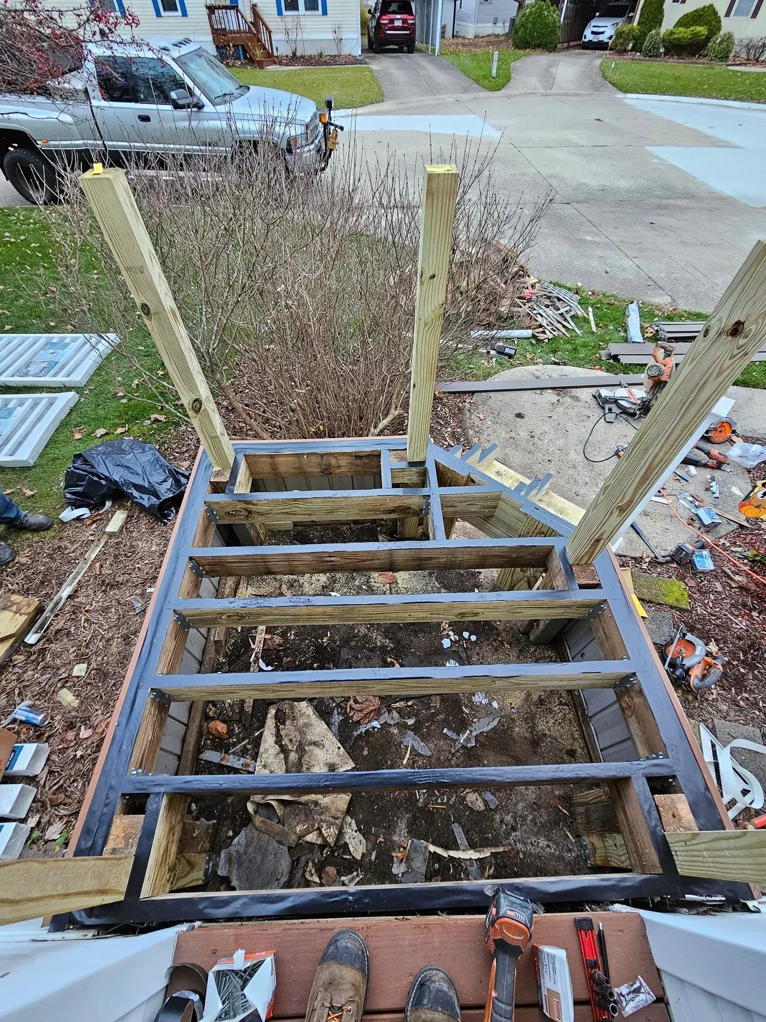 Deck stairs under construction; framework with vertical support posts. Tools and debris are visible.