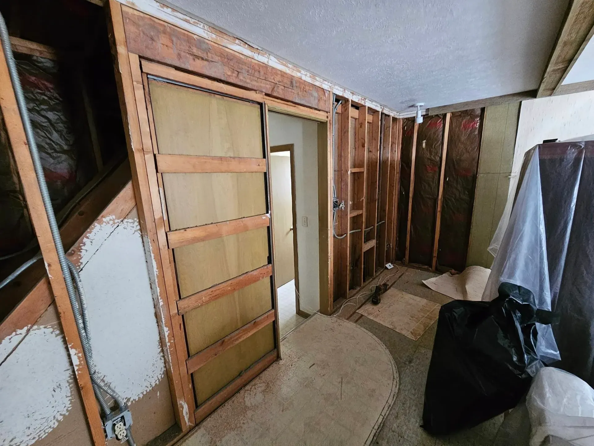 Room under renovation with exposed studs, insulation, and a sliding door.