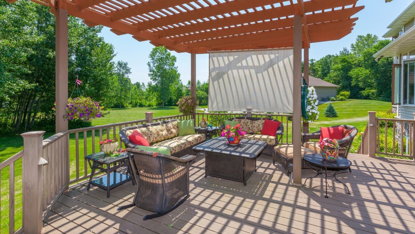 A deck with a pergola and a couch and chairs on it.
