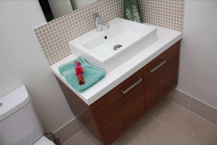 white solid surface bathroom sink with brown drawers