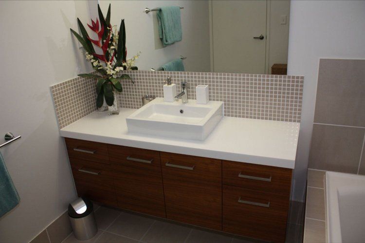 white solid surface bathroom sink with plant