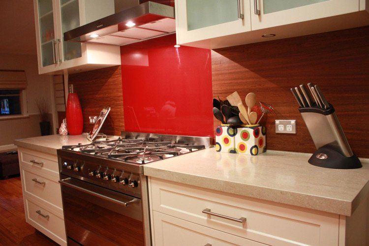 white solid surface counter with stove and red wall behind