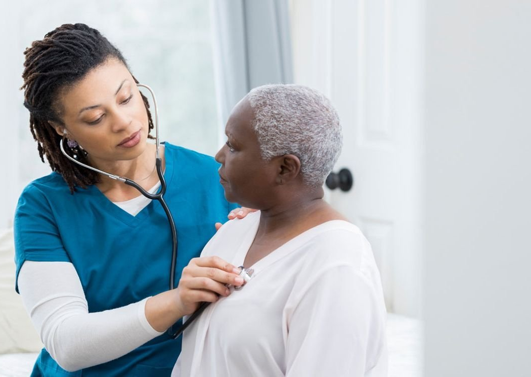 nurse taking the heartbeat of an elderly woman.