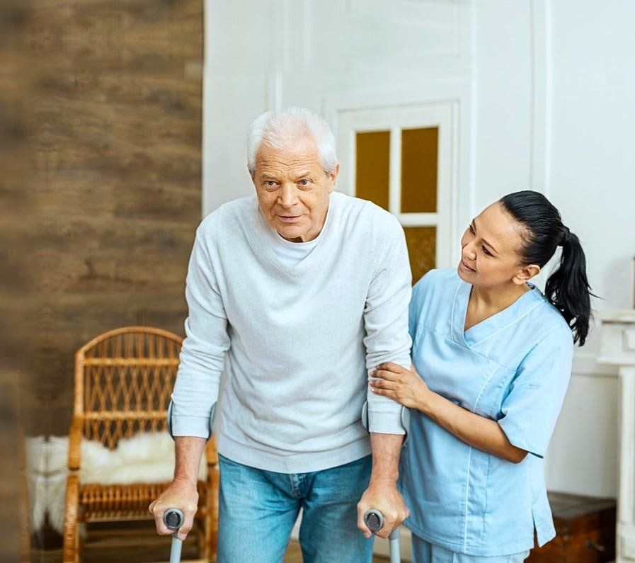nurse helping an elderly man walk using his walker at home.