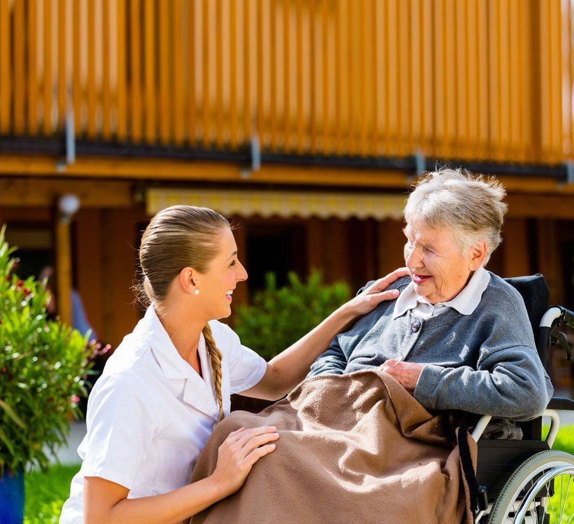 caregiver conversing with a smiling senior patient in a wheelchair.