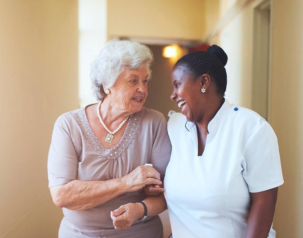 caregiver and elderly women laughing together.