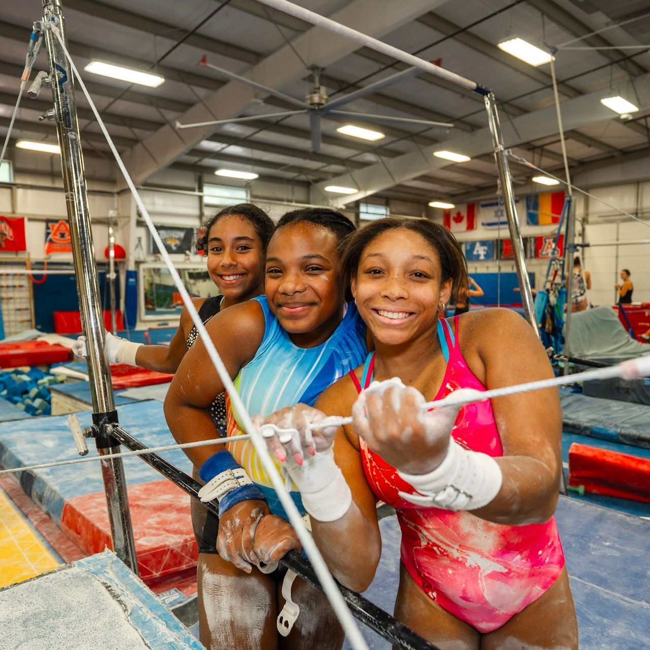 Three women in bathing suits are standing around a bowl of water.