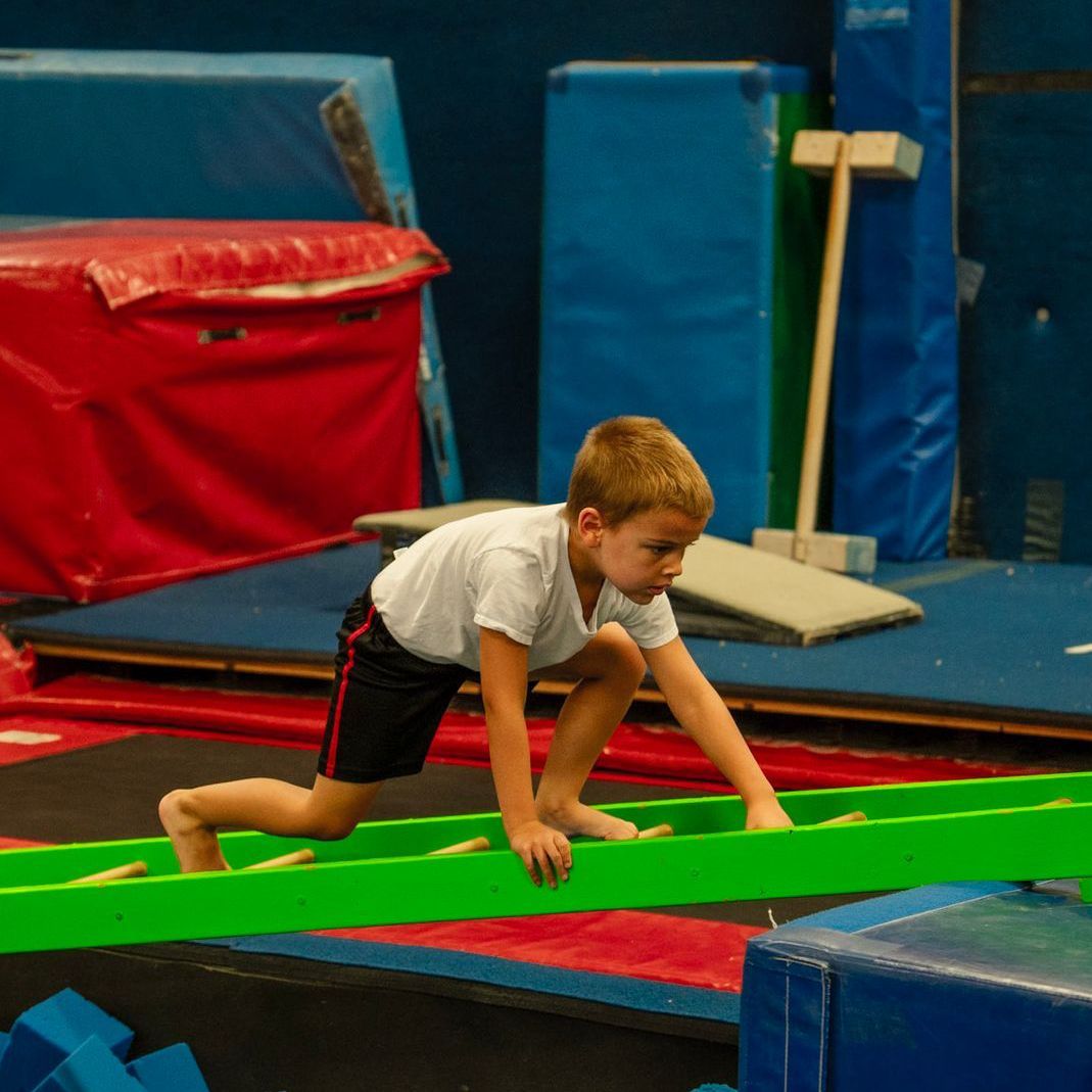 A young boy is hanging on a rope in a gym