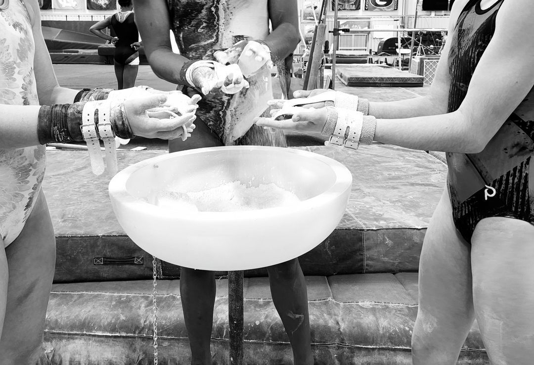 Three women in bathing suits are standing around a bowl of water.