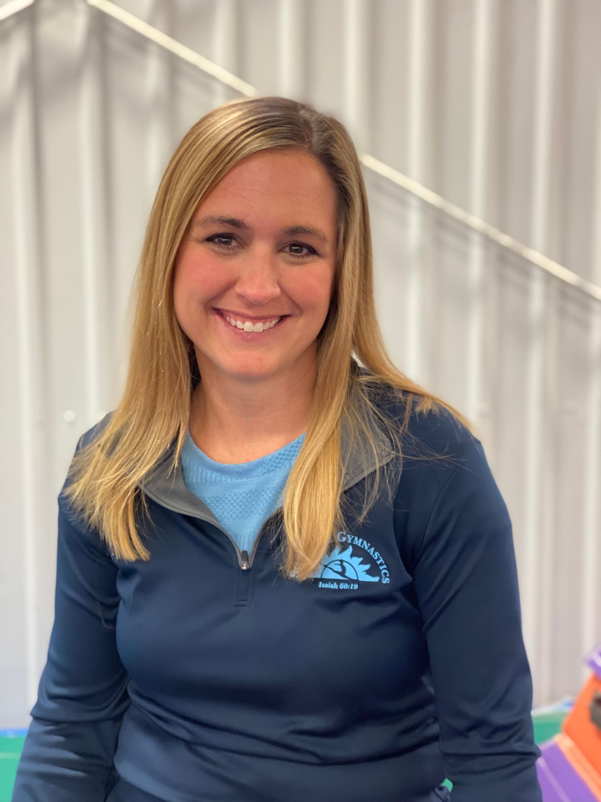 A woman in a blue shirt is smiling for the camera.