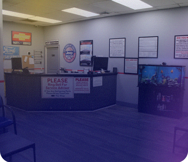 The interior of a service center lobby with a dark service desk, an aquarium, and various automotive brand signage on walls. | Smithwest Service Center