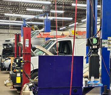 Auto repair shop with vehicles raised on hydraulic lifts, surrounded by equipment and tools in a large garage workspace. | Smithwest Service Center