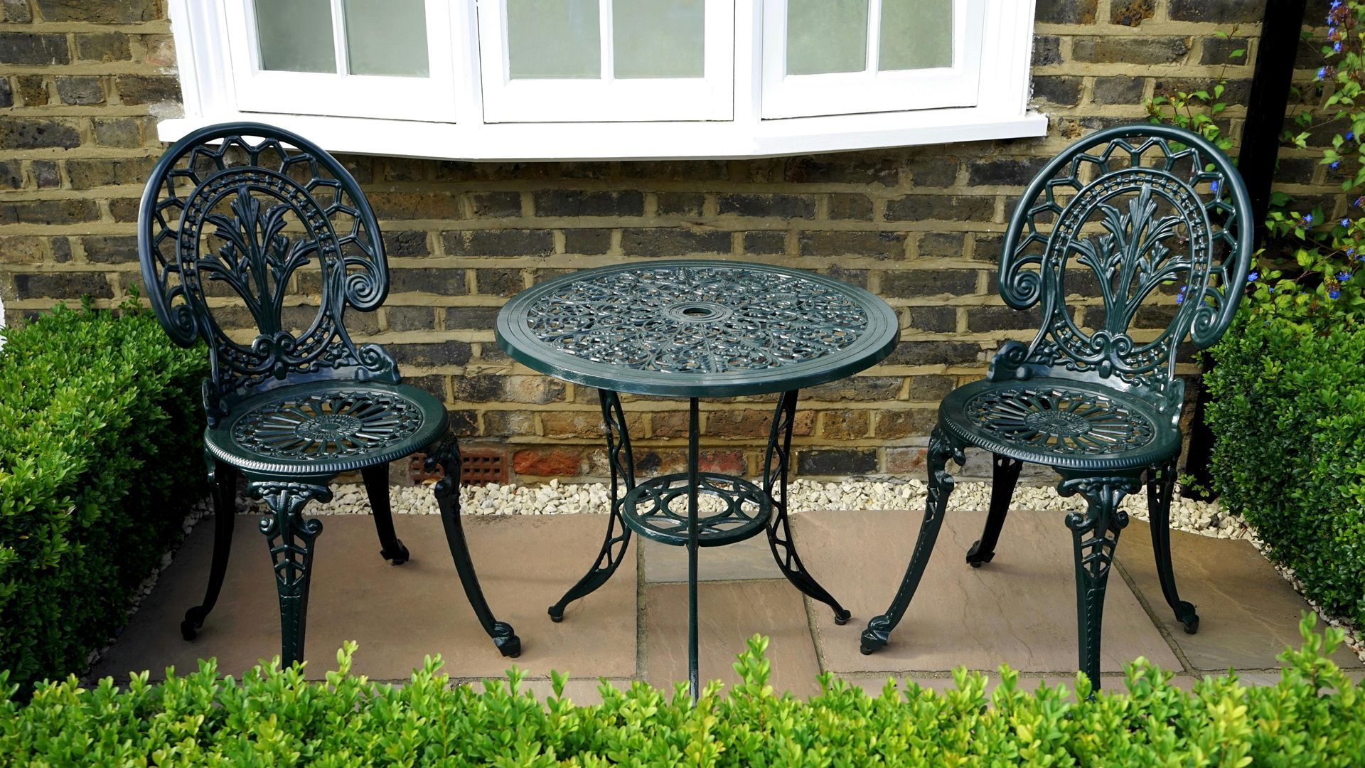 Two chairs and a table in front of a brick building