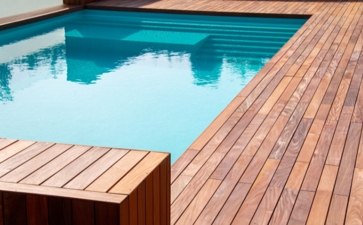 A photo of a luxurious pool deck surrounding a beautiful deep blue pool.