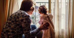 An elderly woman and a little girl are looking out of a window.