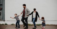 A family is walking down a sidewalk holding hands.