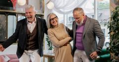 Three older people are standing next to each other in a room.