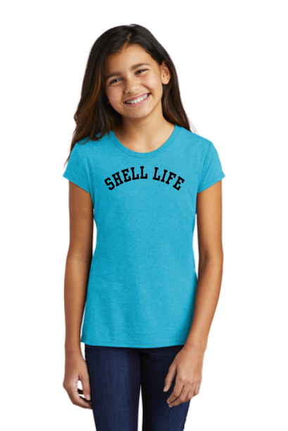 Girl in a turquoise t-shirt that says “SHELL LIFE.” She is wearing jeans.