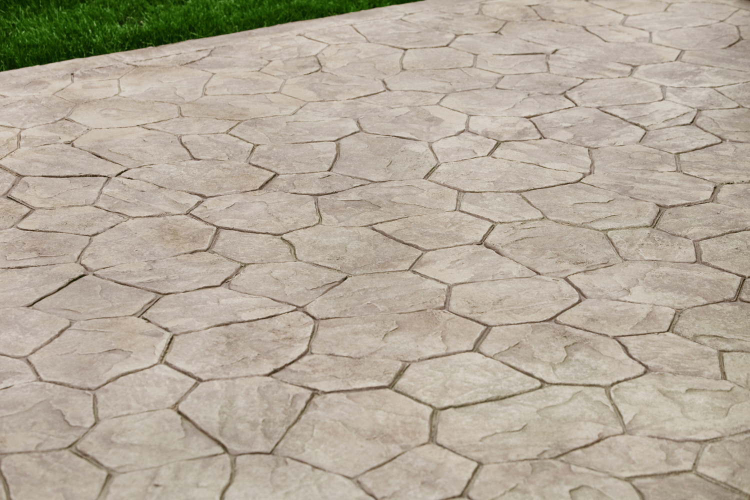A gray patio with a stamped concrete pattern that mimics the appearance of irregularly shaped natural stone pavers.