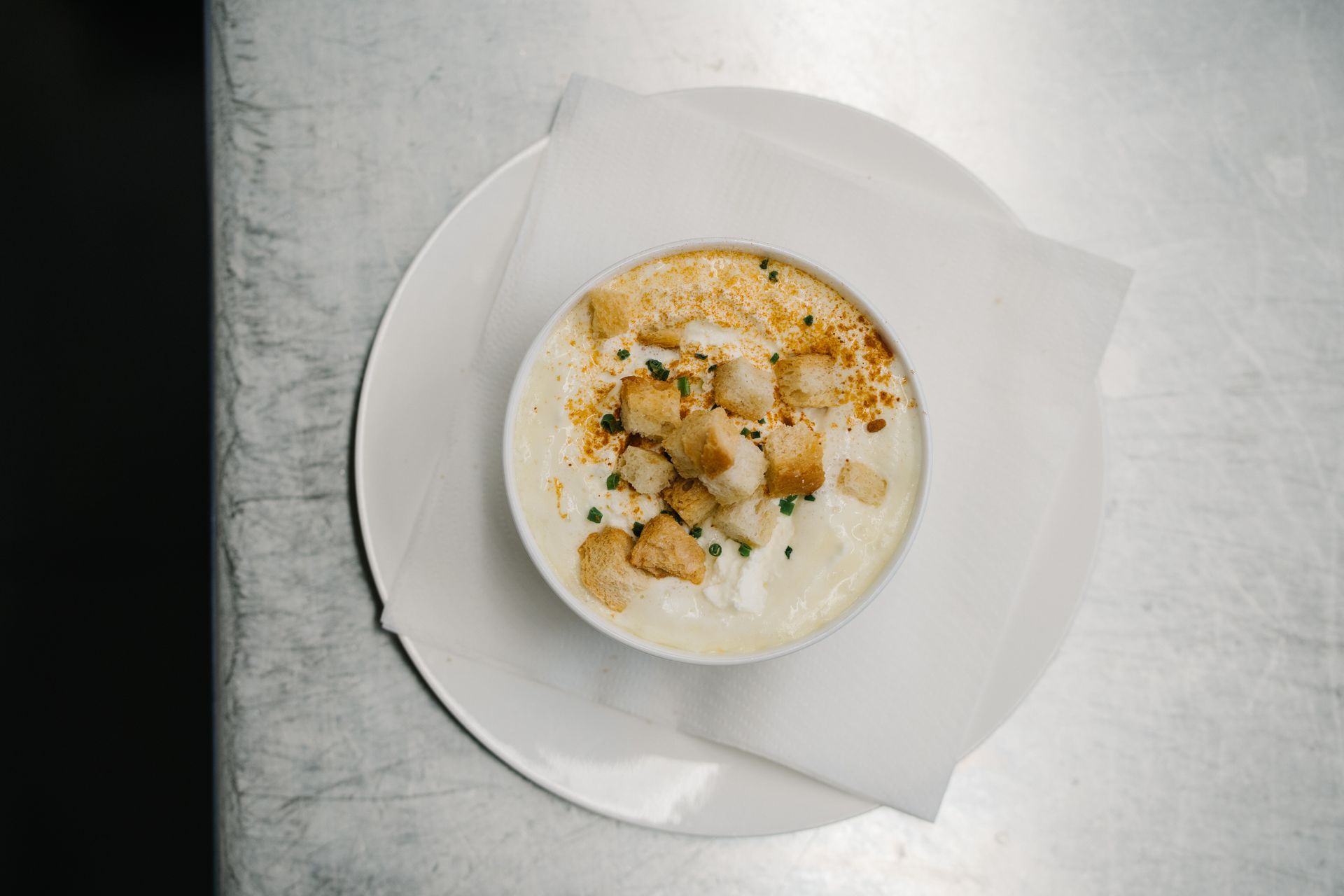 eine Schüssel Suppe mit Croutons auf einem Teller auf einem Tisch.