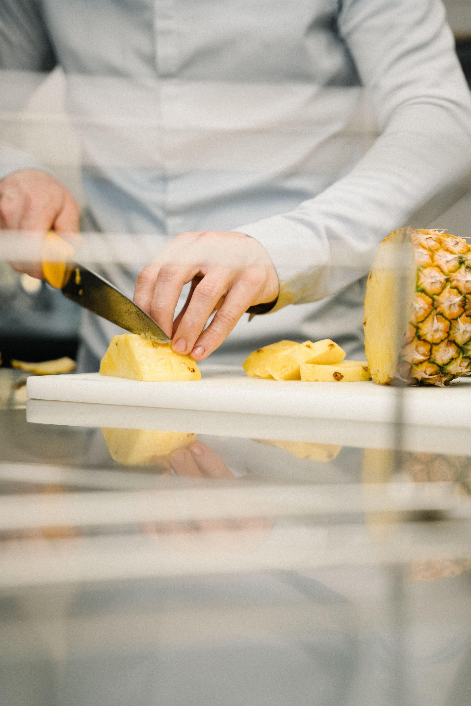 Ein Mann schneidet eine Ananas auf einem Schneidebrett.