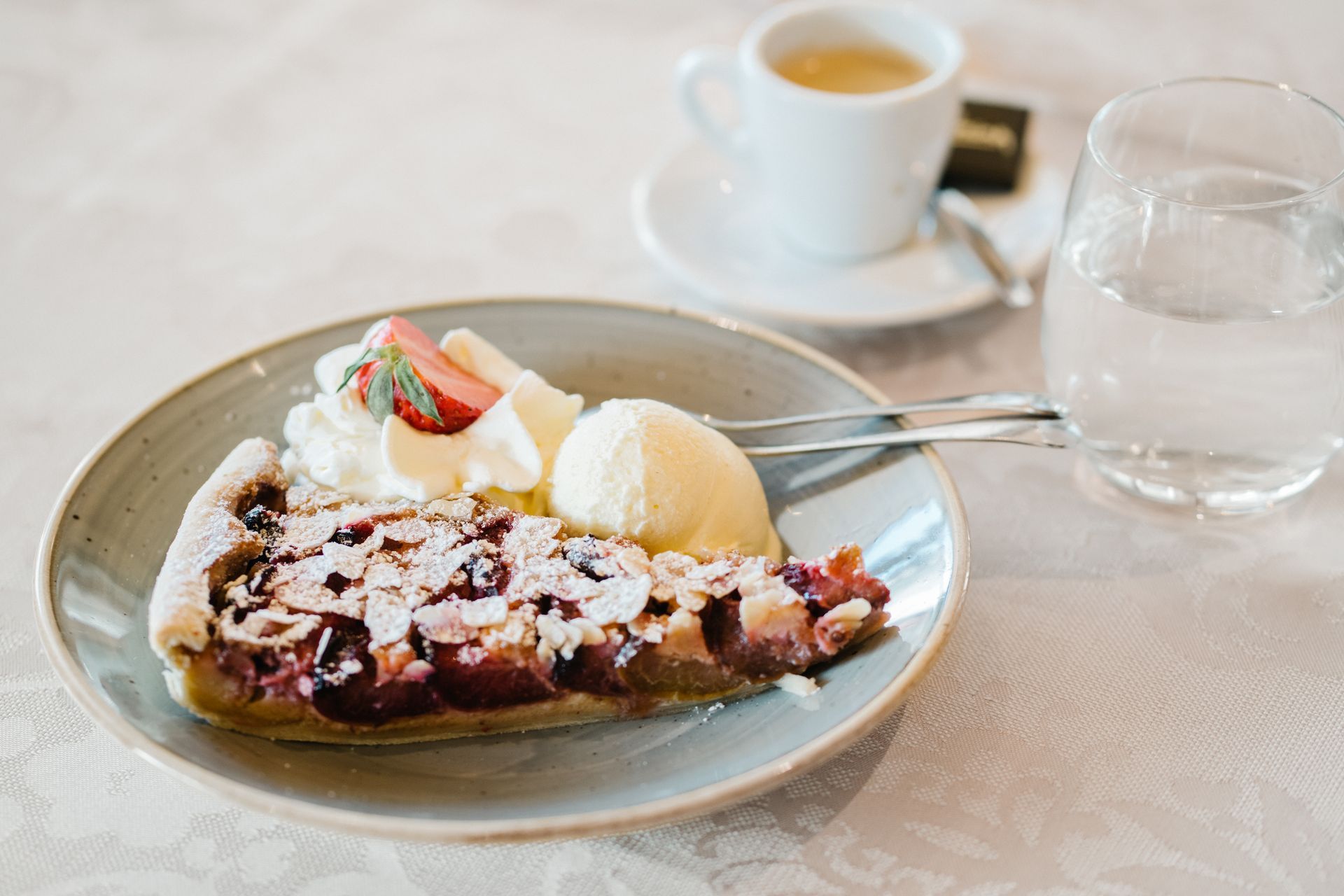 ein Stück Kuchen mit Eis und Schlagsahne auf einem Teller neben einer Tasse Kaffee.