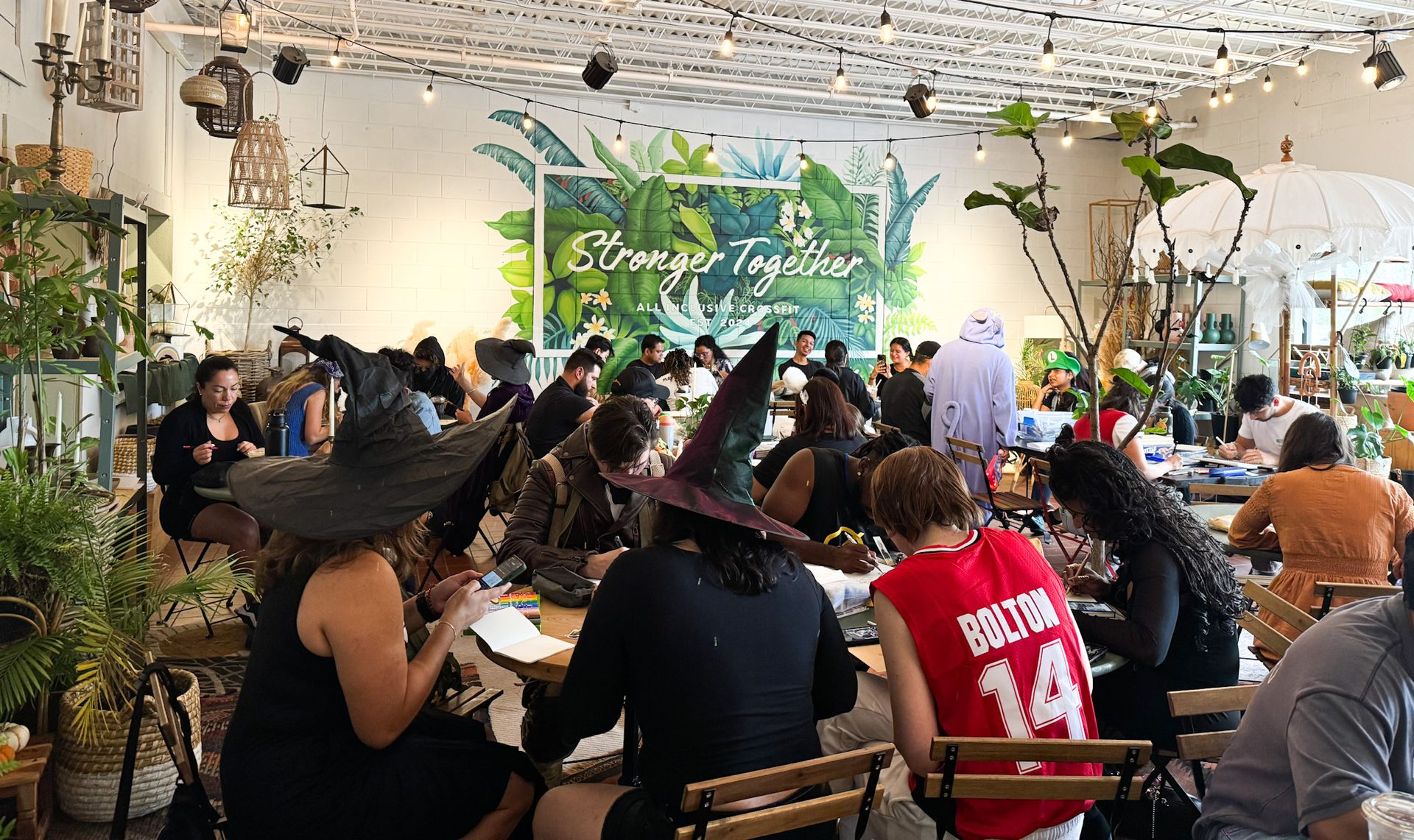 Fall community event inside Harmon Collective in Winter Park. Families and friends in Halloween costumes enjoying Vietnamese coffee, conversation, and drawing.