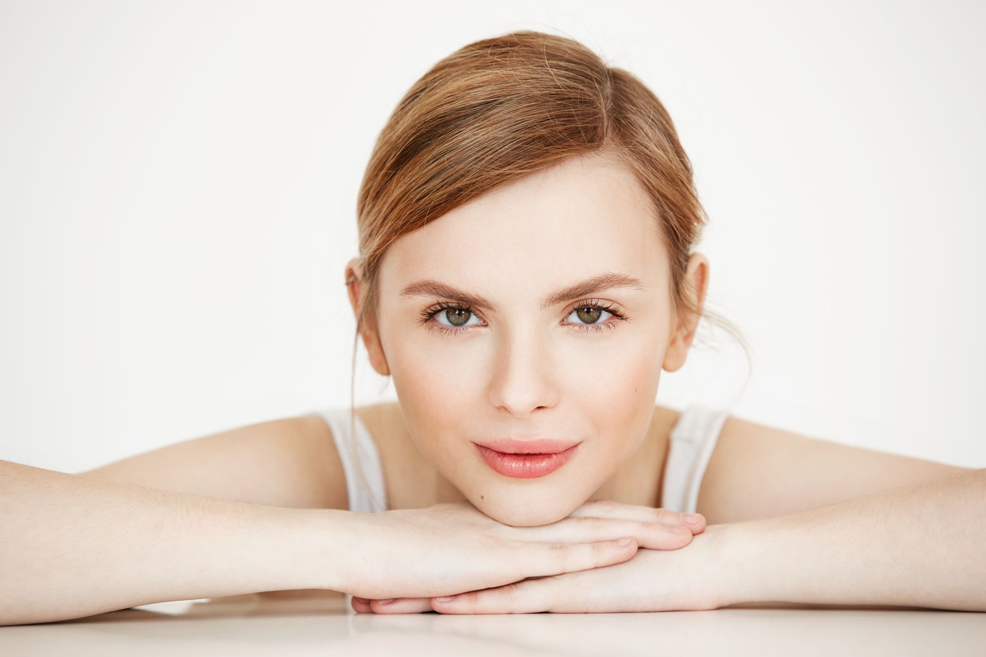 A woman is sitting at a table with her head resting on her hands.