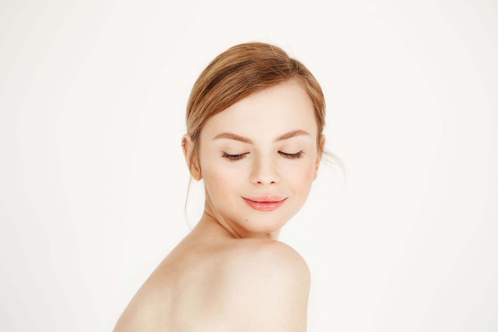 A woman with her eyes closed is looking over her shoulder.