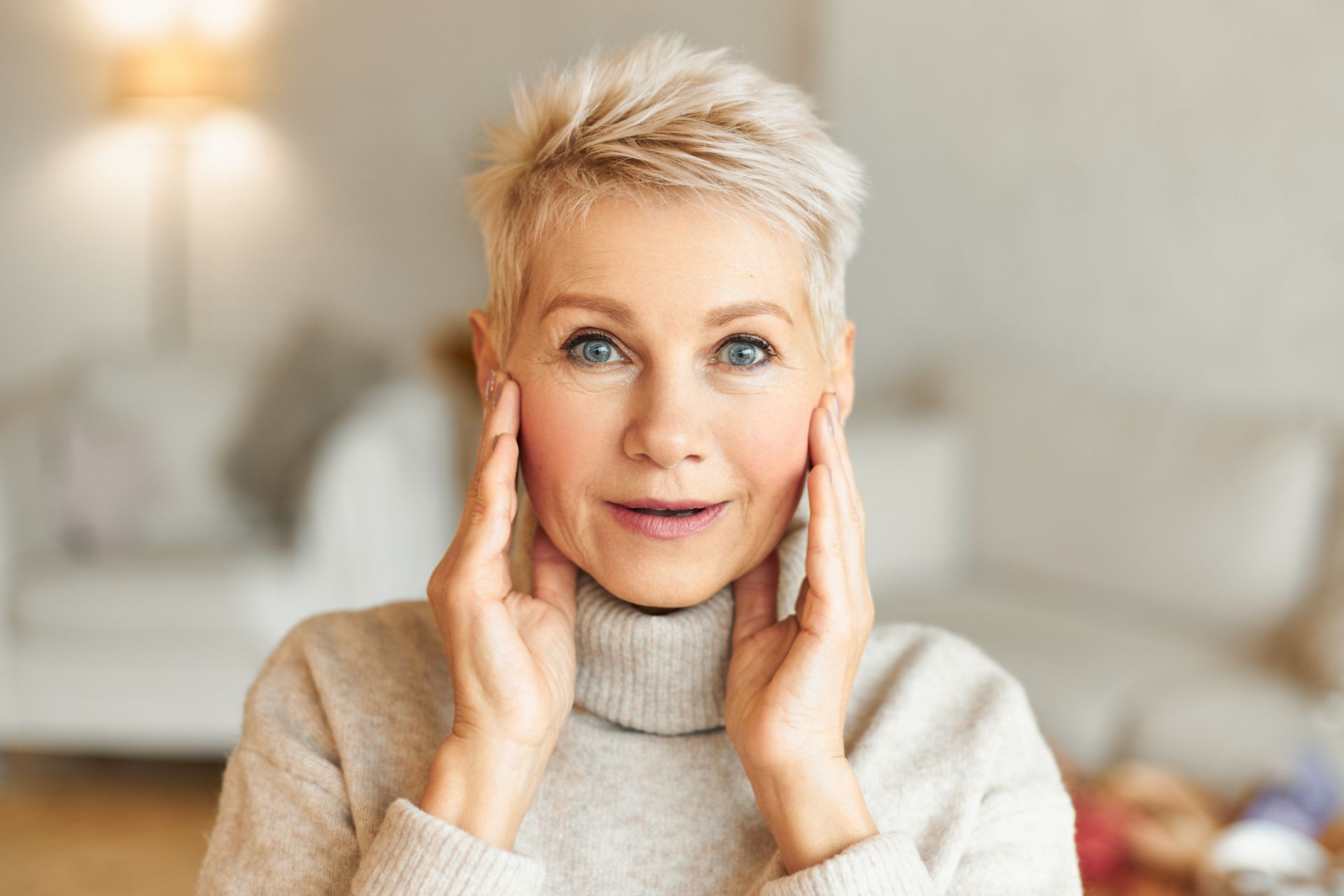 A woman is talking on a cell phone and touching her face.