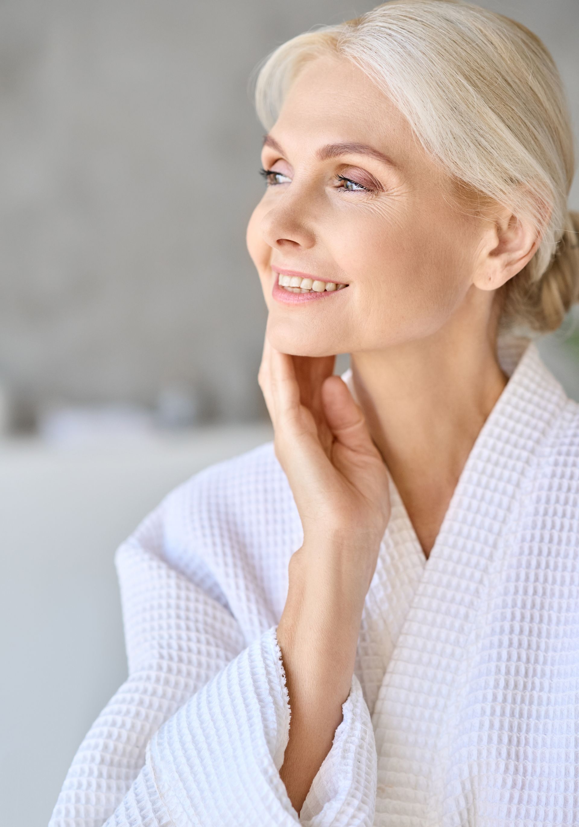 a woman in a white top and blonde hair looking on her side