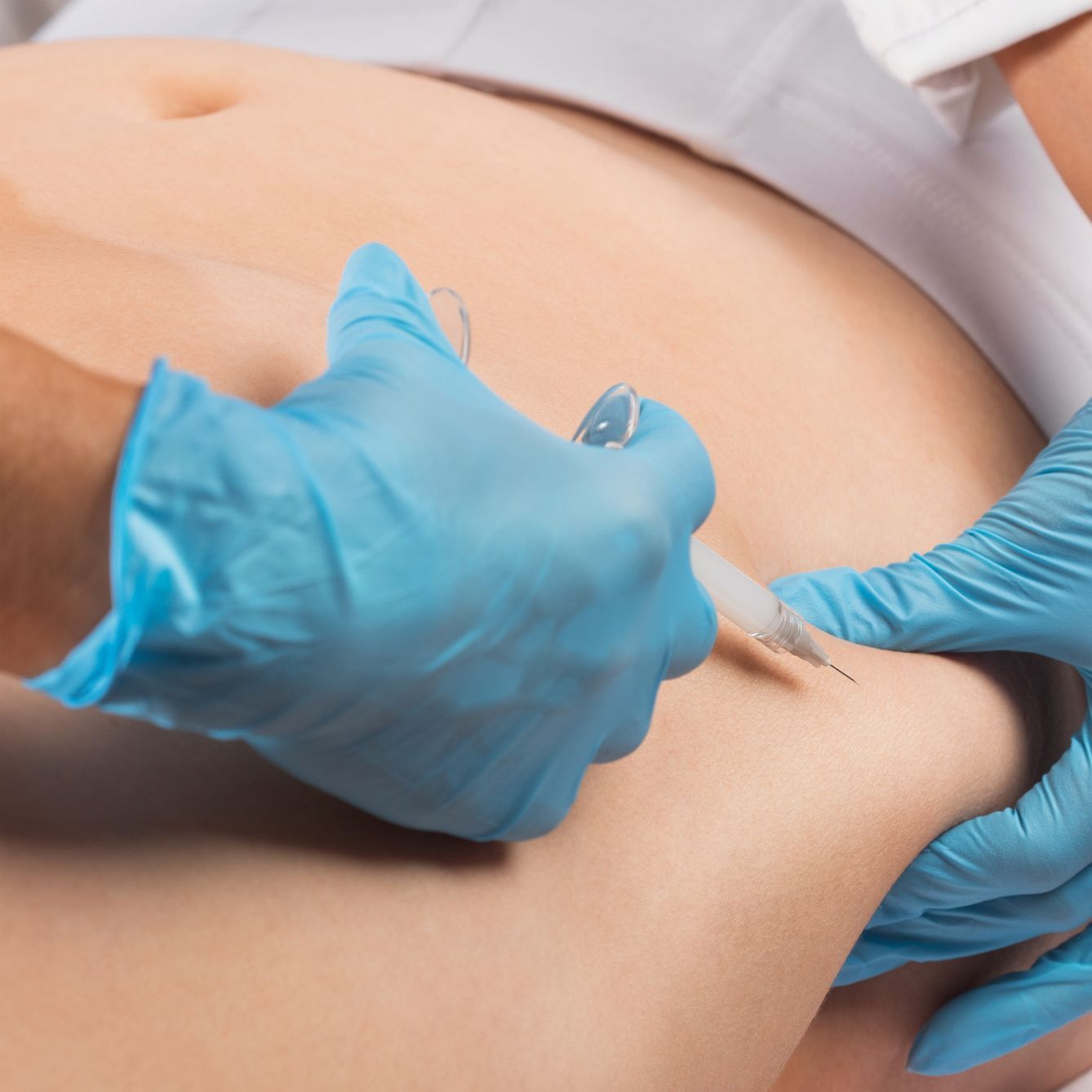 A person wearing blue gloves is giving a person an injection.