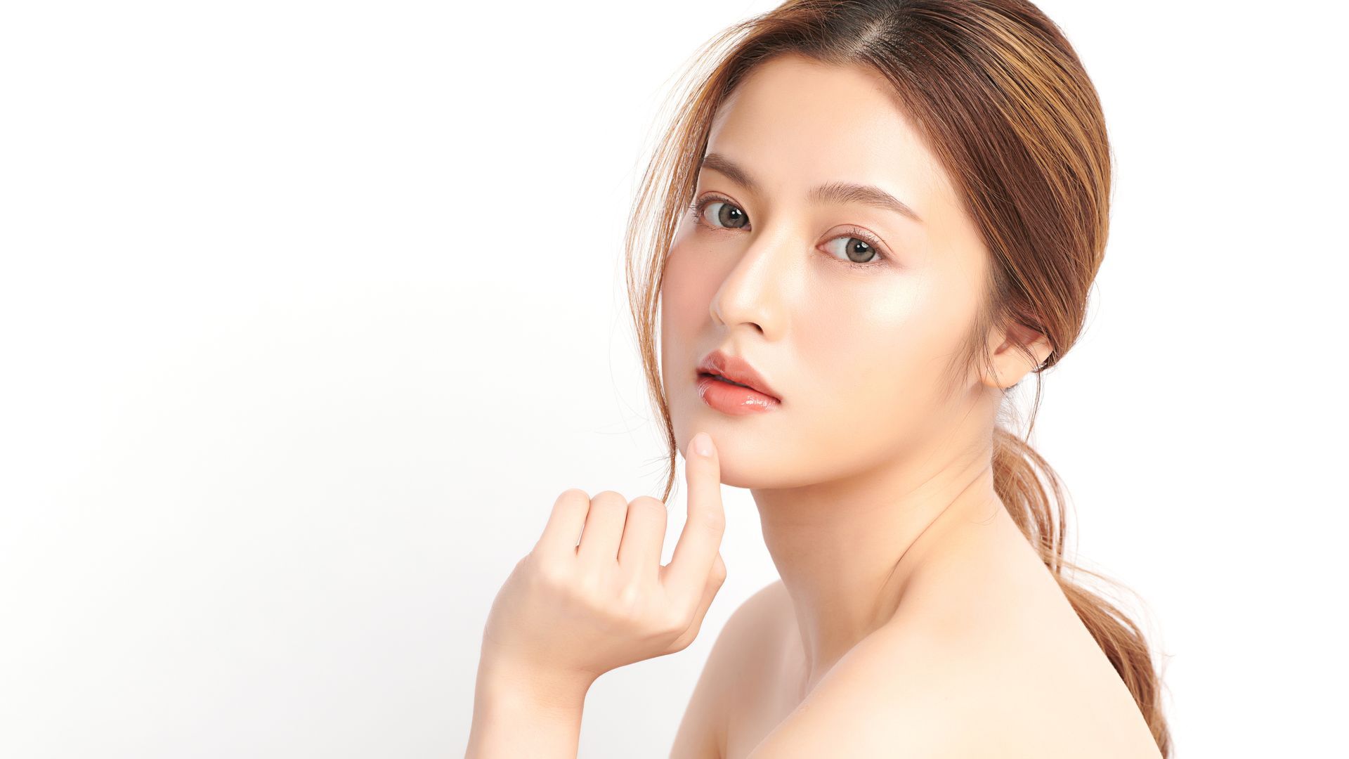 A woman is touching her face with her hand and looking at the camera.