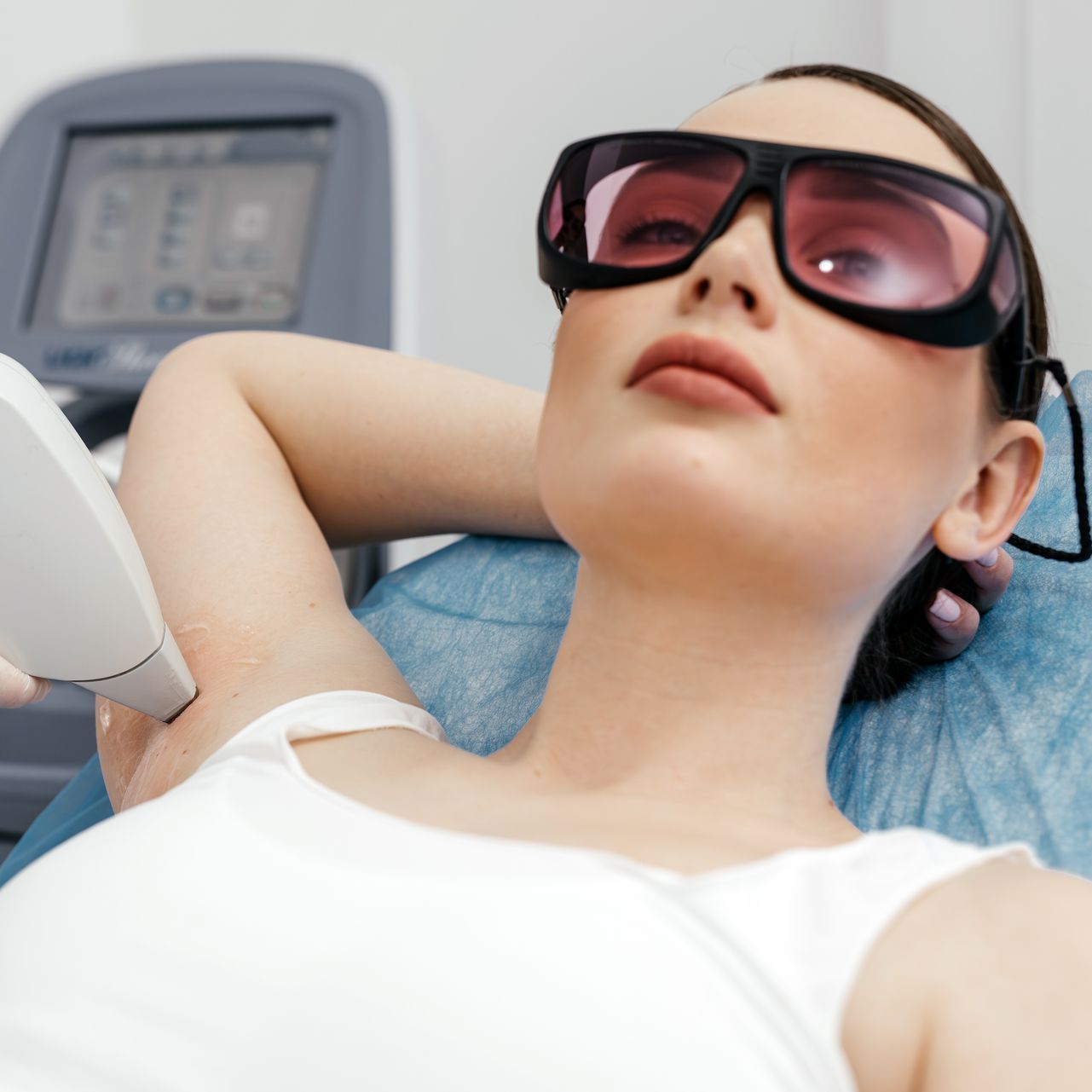 A woman is getting her armpit hair removed by a laser.