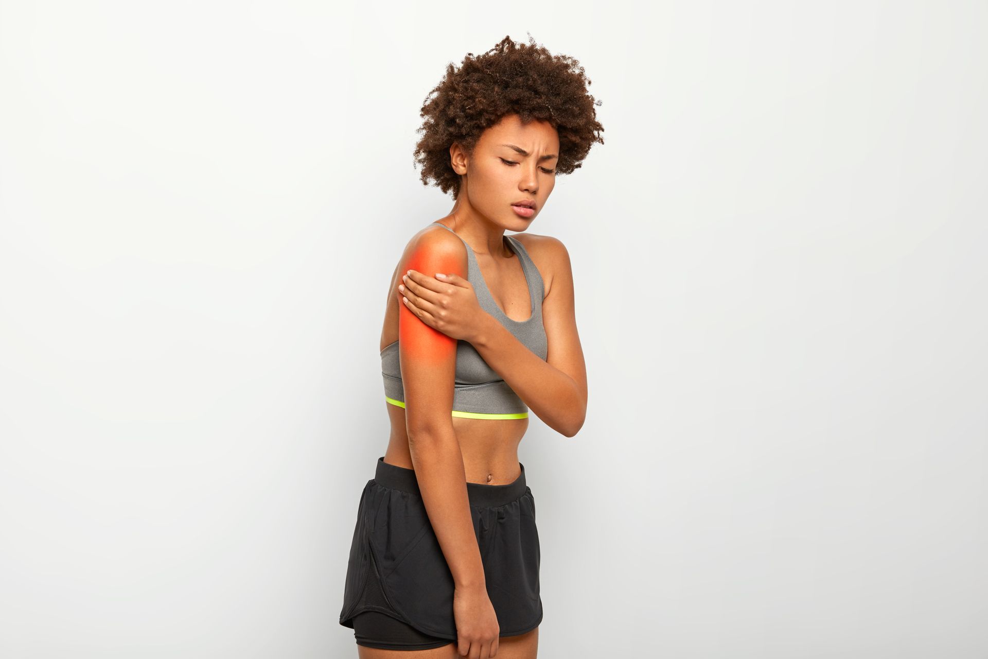 A woman is holding her shoulder in pain.