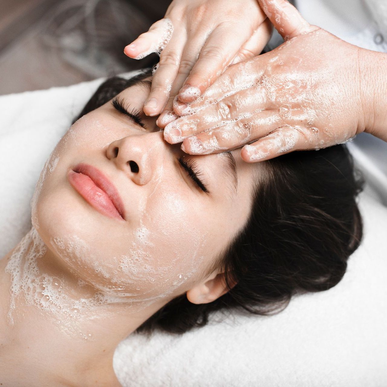 A woman is getting a massage on her face with her eyes closed